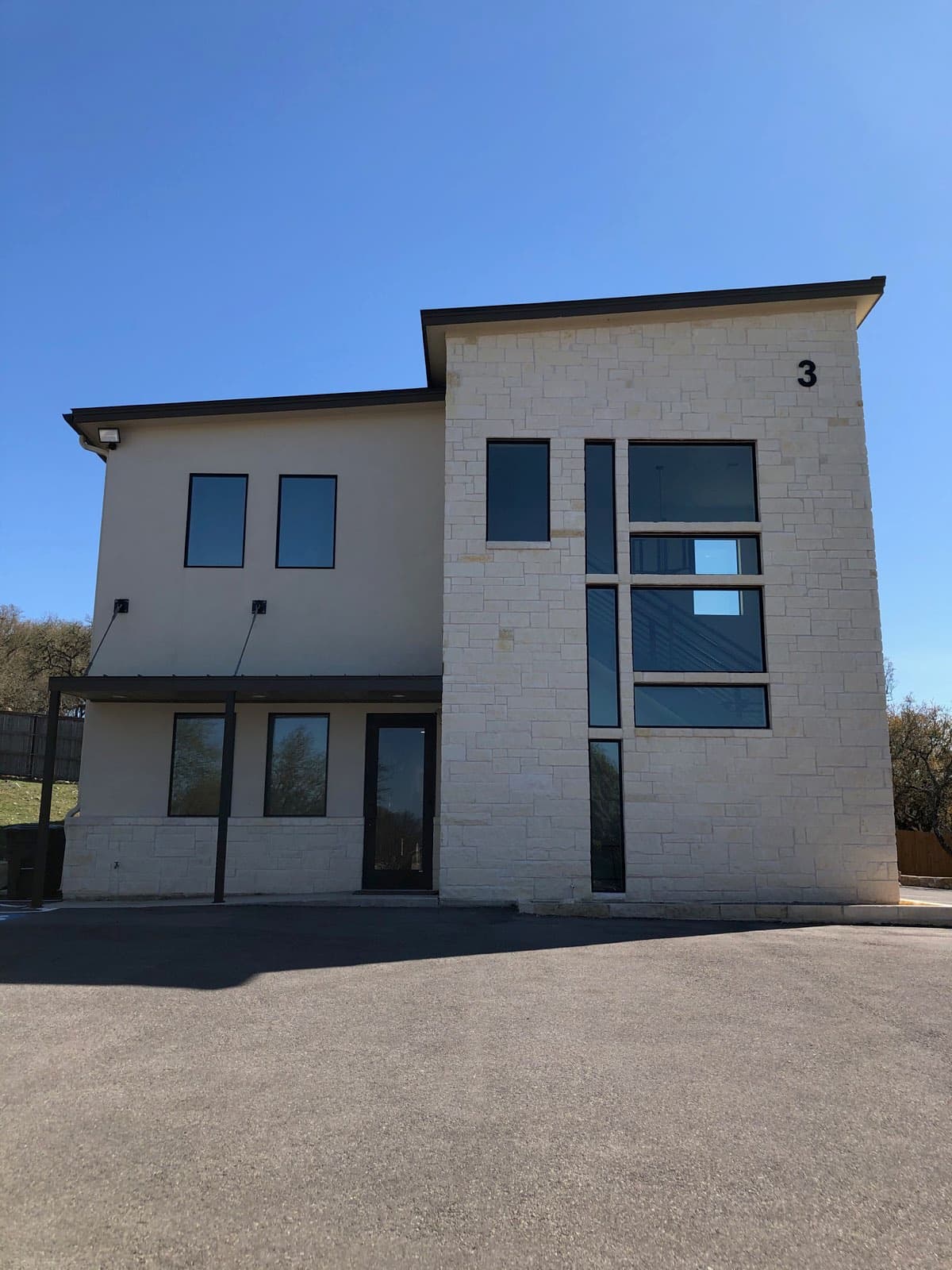 Building 3 at 8000 Fair Oaks Pkwy: a two-storey limestone and stucco building with dark window frames, a covered walkway, and a large numeral 3 near the roofline.